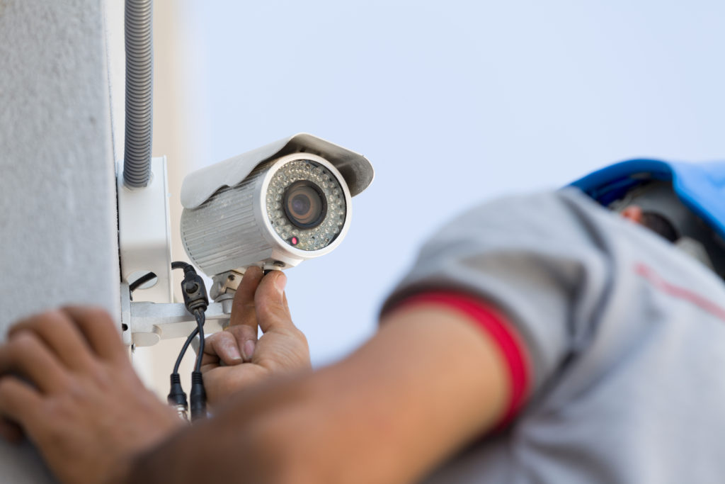 Close up of an CCTV installer carrying out an installation of a white CCTV camera